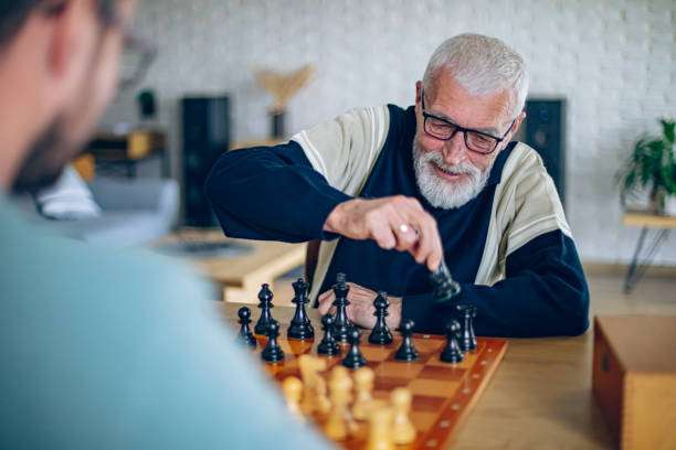 Elderly man playing chess on a chessboard with focus.