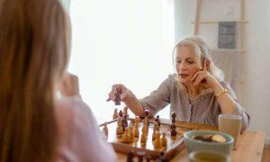 The living room is alive with concentration as a grandmother and granddaughter strategize over a chess board, enjoying their time together.
