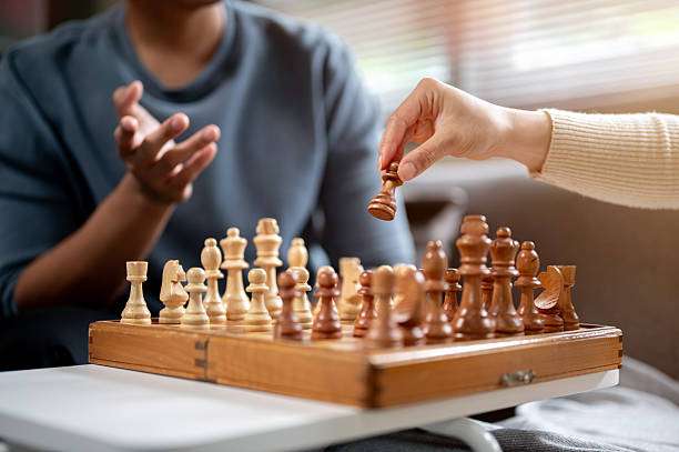 Close-up of a person moving a pawn on a wooden chess board during a game.