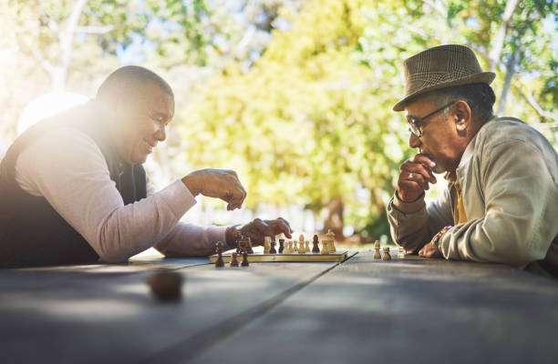 Two men playing chess on a chess board outdoors.