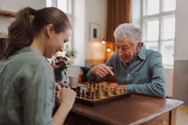 Grandfather and granddaughter enjoy a game of chess on a chessboard.