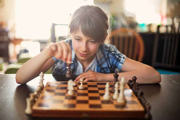 Teenage girl playing a game of chess board. A smart girl aged 10 is making her move.