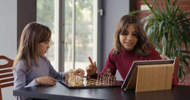 Two child girls playing chess together on a chess board.