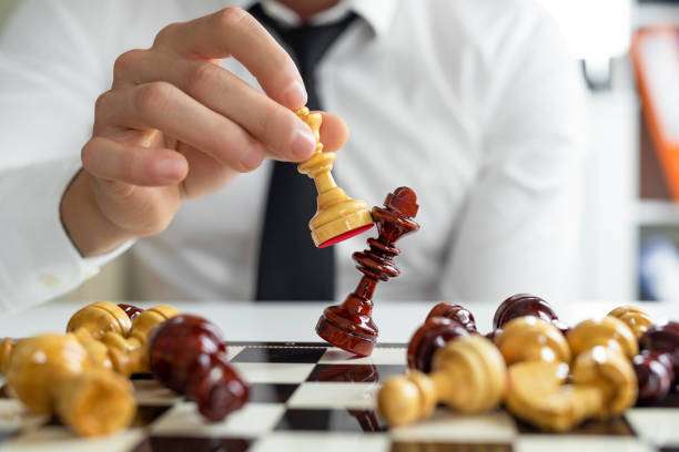Businessman moving chess piece on chess board game