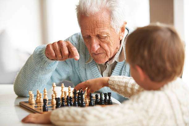 Grandfather teaching child to play chess board game.