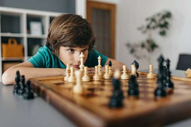 Young boy intensely concentrating on a chess board game.