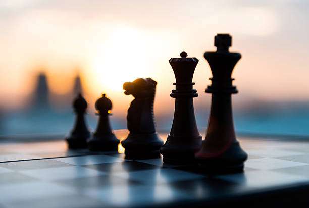 Silhouette of chess pieces on a chessboard at sunset.