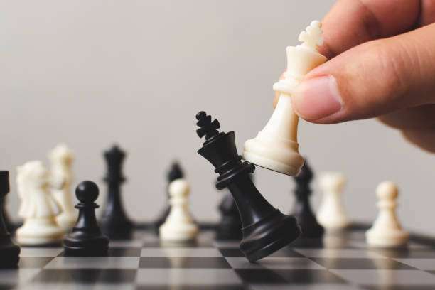 Hand moves white king to checkmate black king on a chess board.