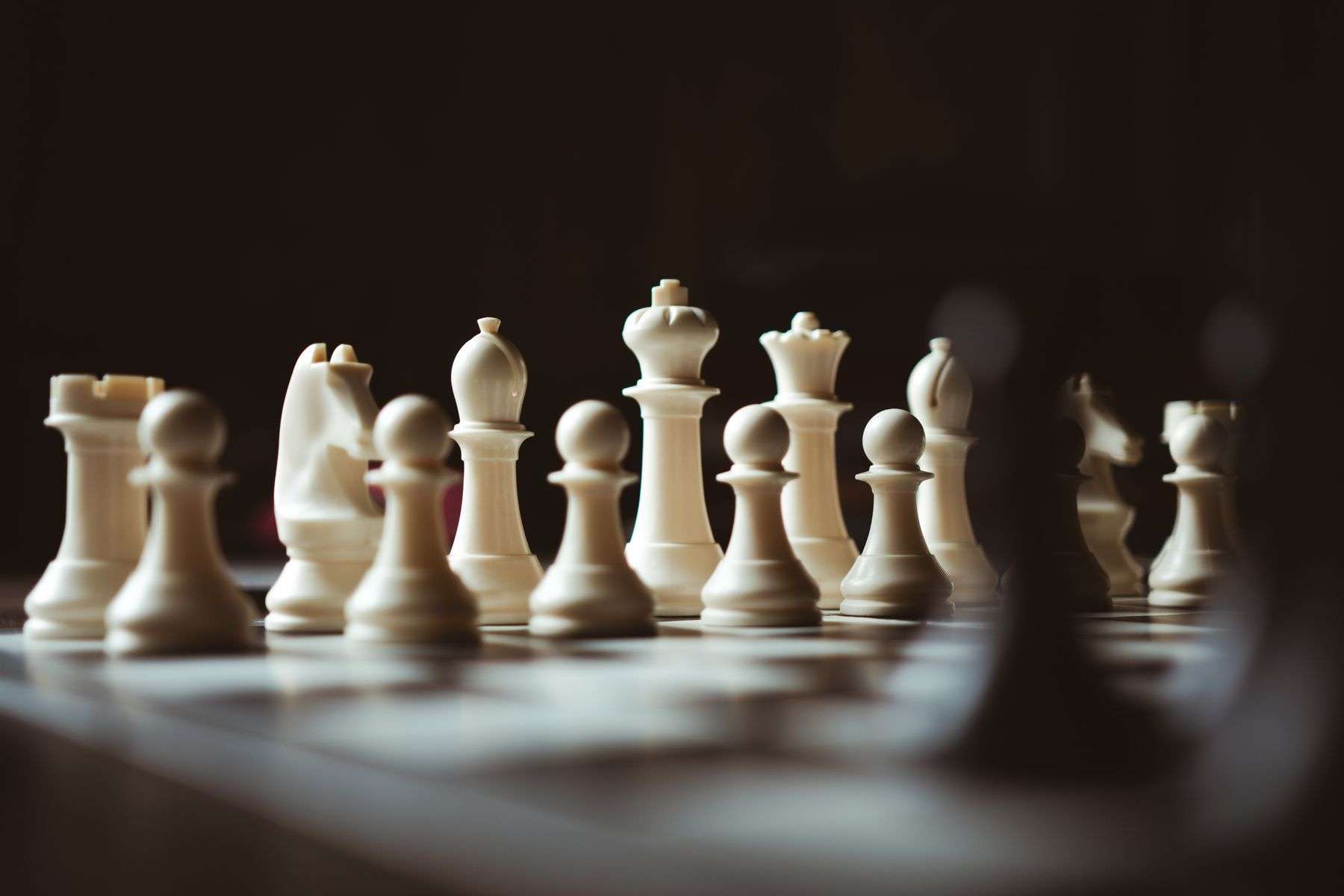 Recognizable light and dark chess-piece silhouettes on a board