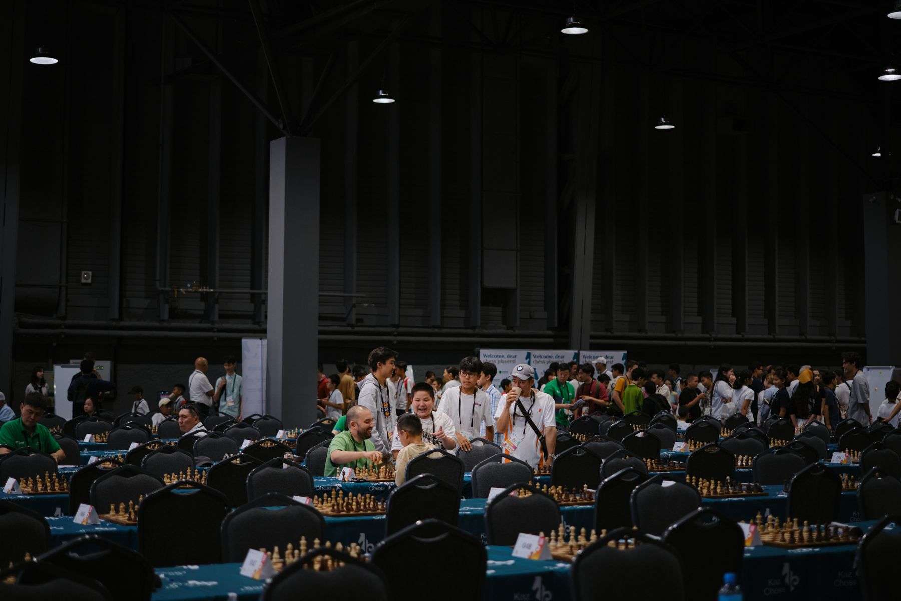 Players gathered around boards in an indoor chess tournament hall